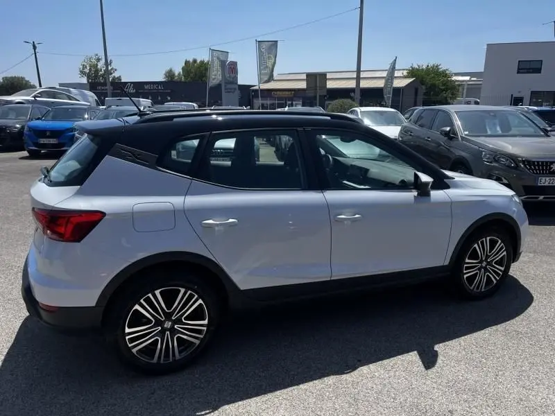 Vue de profil côté gauche d'un SEAT Arona blanc 2024 avec toit noir et jantes alliage distinctives.