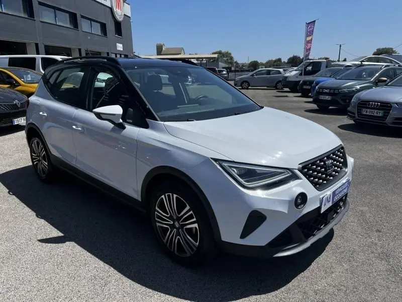 SEAT Arona blanc vue 3/4 avant droit, avec calandre noire et jantes alliage distinctives, stationné en extérieur.