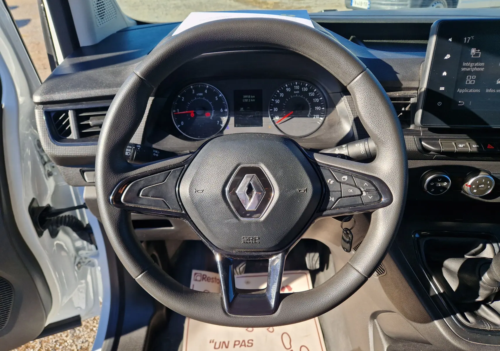 Vue rapprochée du volant noir d’un Renault Kangoo blanc 2023, avec tableau de bord et écran tactile visibles.