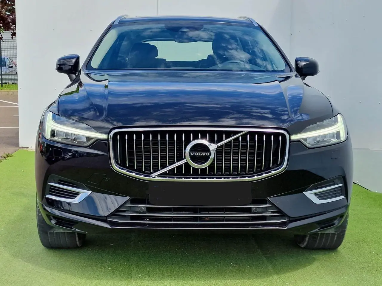 Vue frontale du Volvo XC60 noir 2021 avec calandre chromée et phares LED allumés.