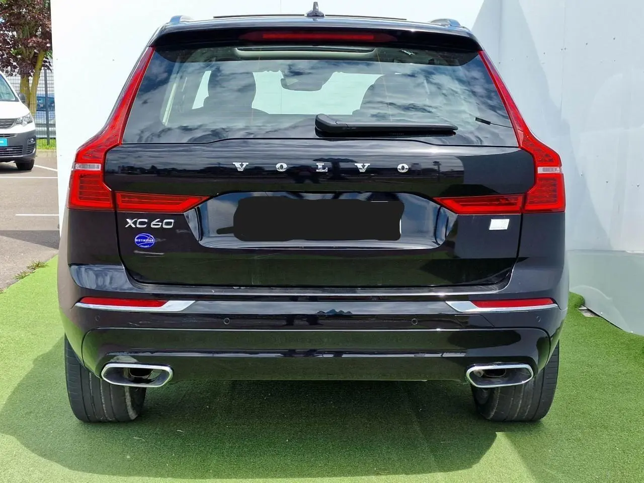 Vue arrière d'un Volvo XC60 noir avec feux arrière en forme de L et double sortie d'échappement chromée.