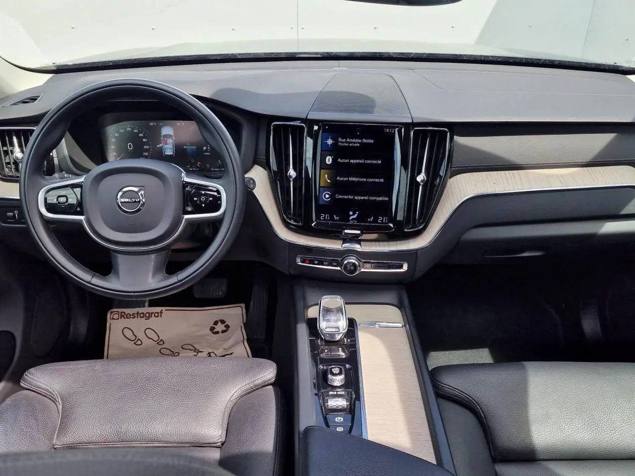 Vue intérieure du tableau de bord et console centrale du Volvo XC60 noir avec écran tactile vertical et volant multifonction.