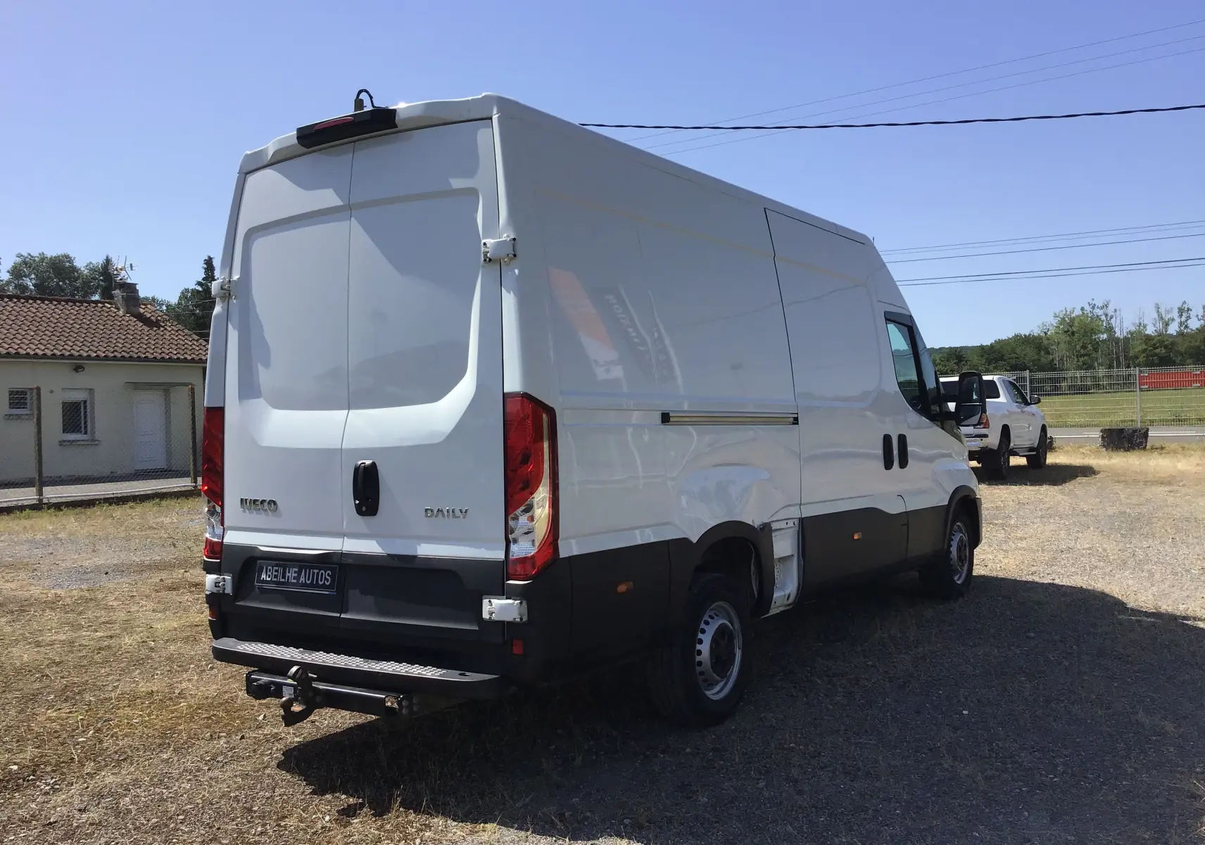 Fourgon blanc Iveco Daily 2022 vu en 3/4 arrière droit, avec hayon et marchepied arrière visible.