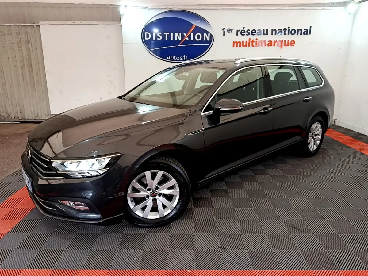 Volkswagen Passat break gris foncé vue 3/4 avant droit dans un showroom intérieur avec logo Distinxion en arrière-plan