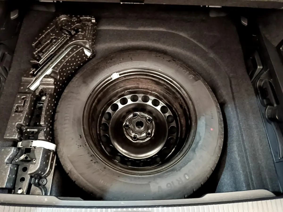 Vue plongeante sur la roue de secours acier noire dans le coffre gris foncé d'une Volkswagen Passat 2021.