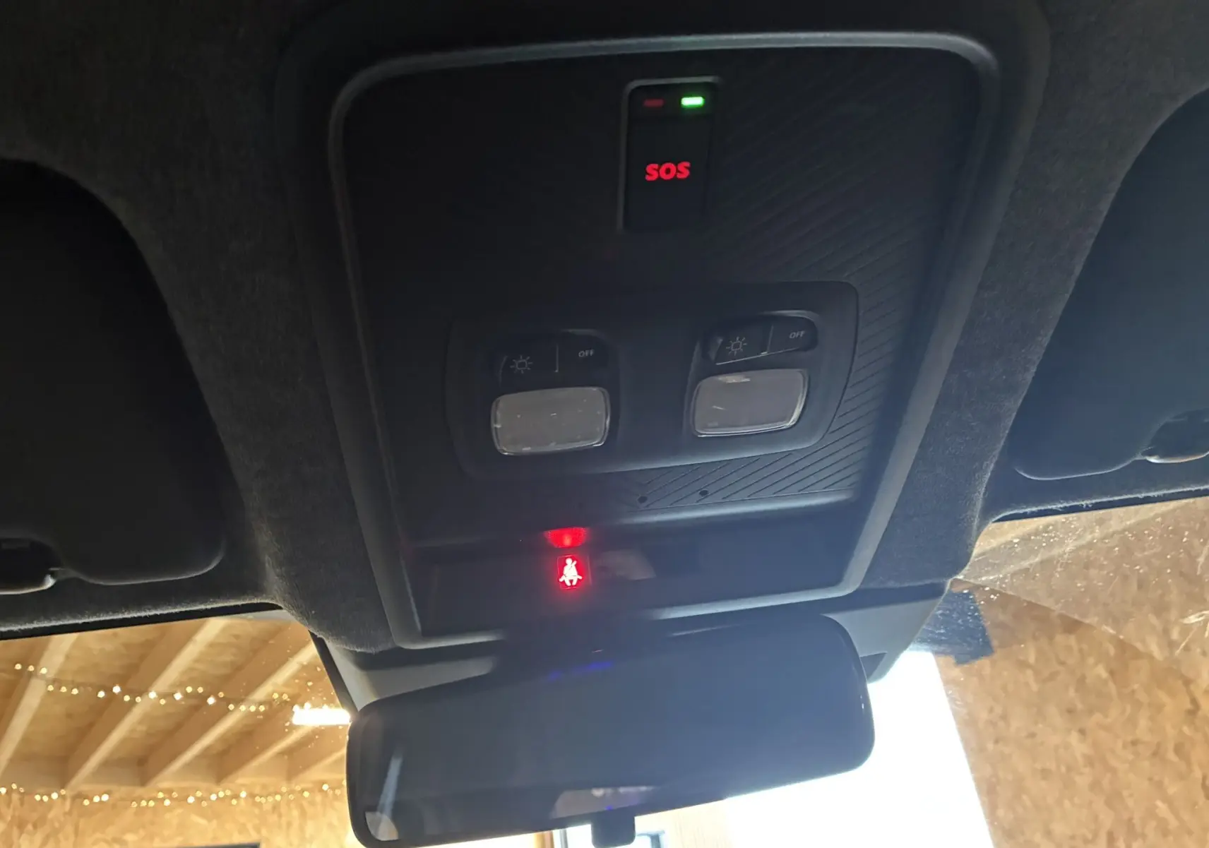 Vue intérieure du plafonnier du Dacia Duster noir 2025, avec boutons d’éclairage et témoin SOS allumé.