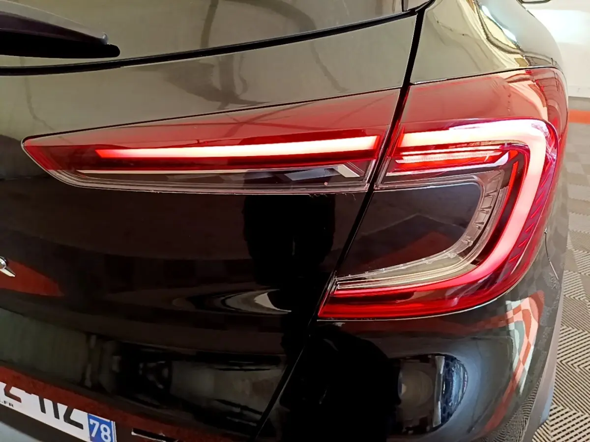 Gros plan sur le feu arrière droit rouge et blanc du Renault Captur Business noir, soulignant la finition moderne et brillante.