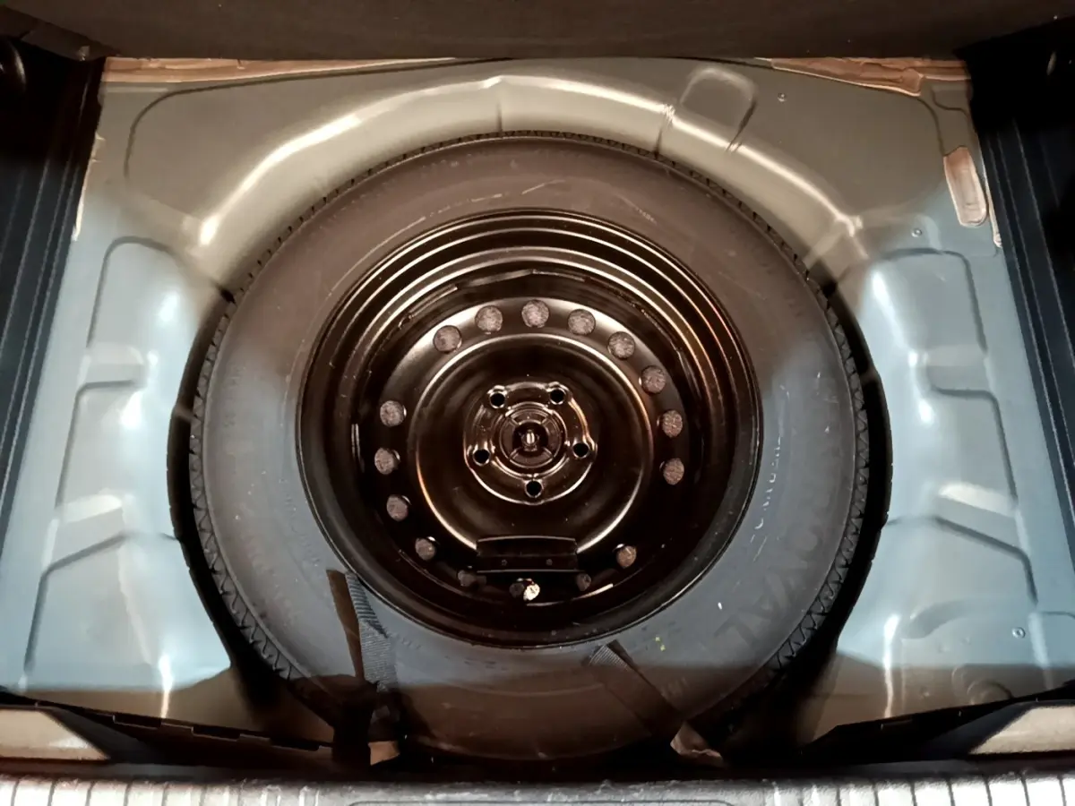 Roue de secours noire vue de dessus dans le coffre d’un Renault Captur Business Blue dCi 115 EDC 2021.