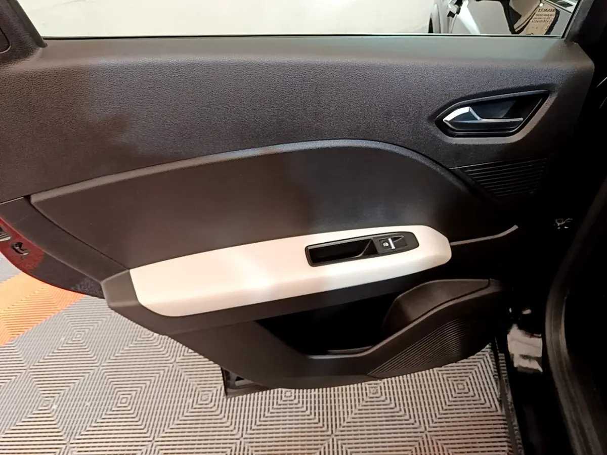 Vue rapprochée de la porte intérieure côté gauche du Renault Captur Business noir, avec poignée argentée et commande de vitre.