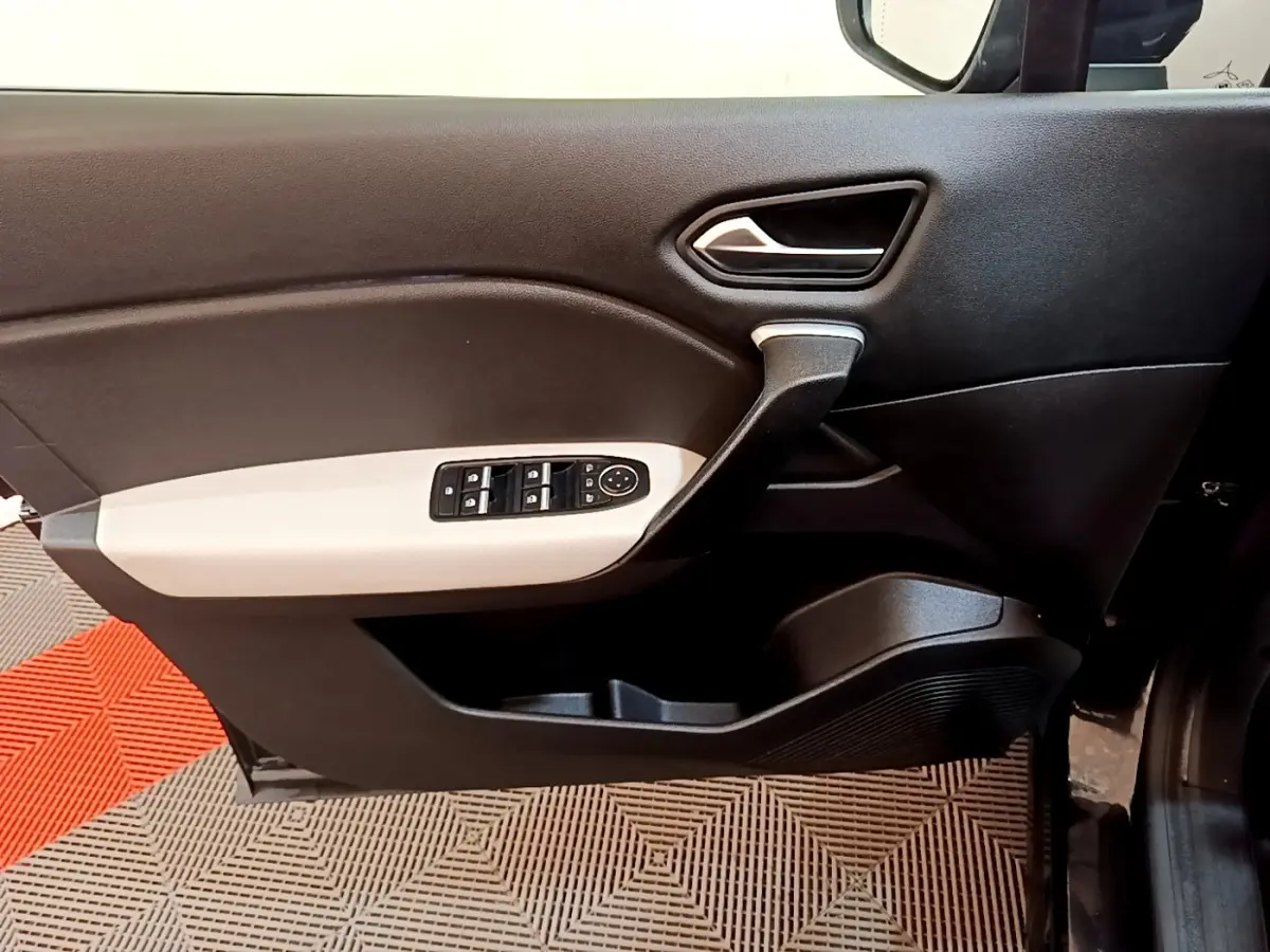 Vue intérieure du panneau de porte avant gauche du Renault Captur noir, avec commandes électriques des vitres et poignée argentée.