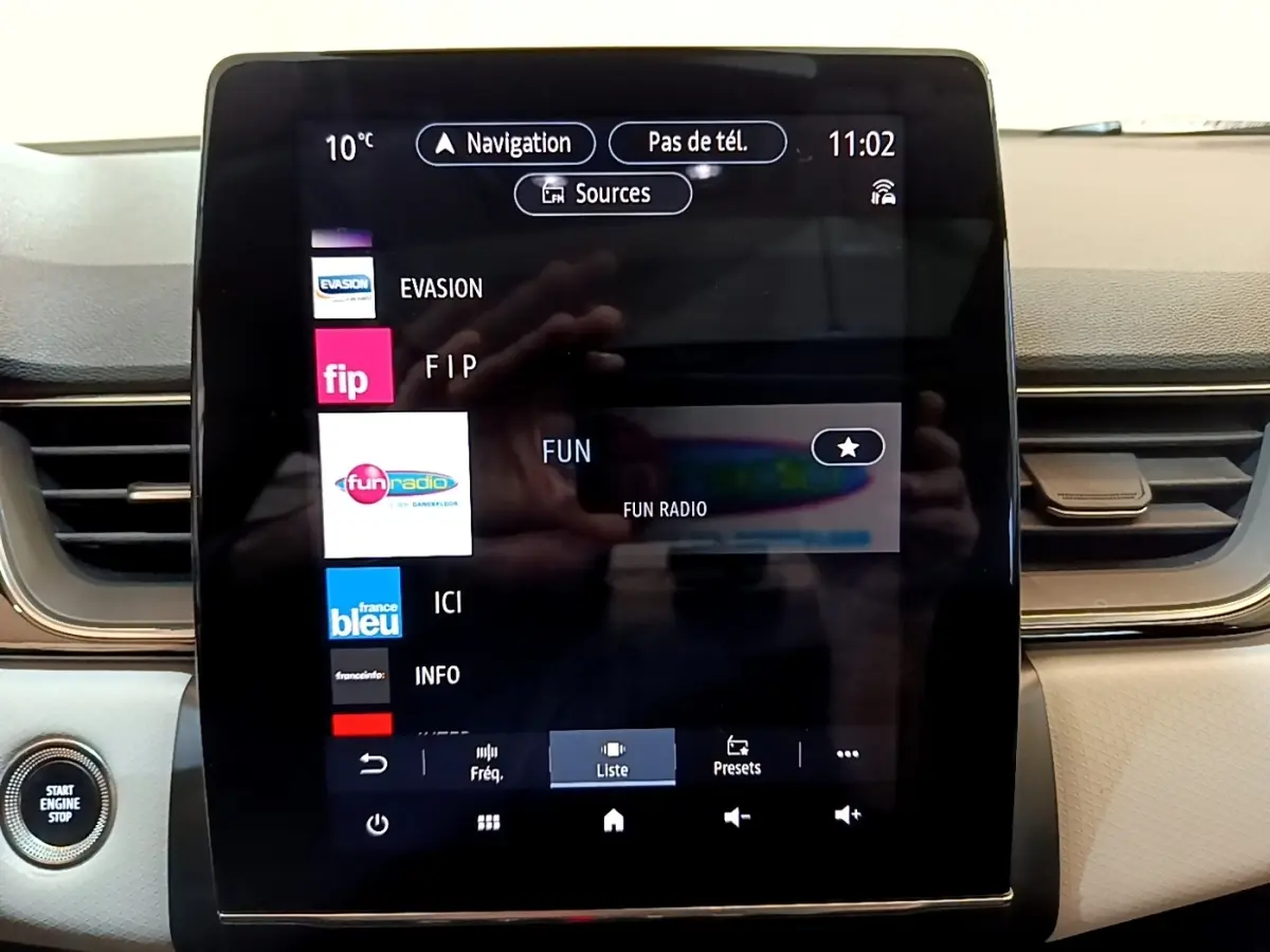 Écran tactile central du tableau de bord du Renault Captur Business noir, affichant les stations radio avec bouton démarrage visible.