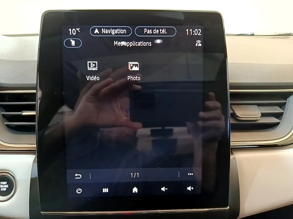 Gros plan sur l'écran tactile central du tableau de bord du Renault Captur Business noir, avec affichage des applications vidéo et photo.