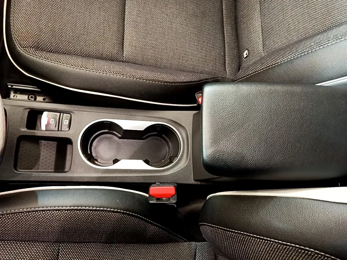 Vue plongeante sur la console centrale noire du Renault Captur 2021, avec porte-gobelets et accoudoir cuir.