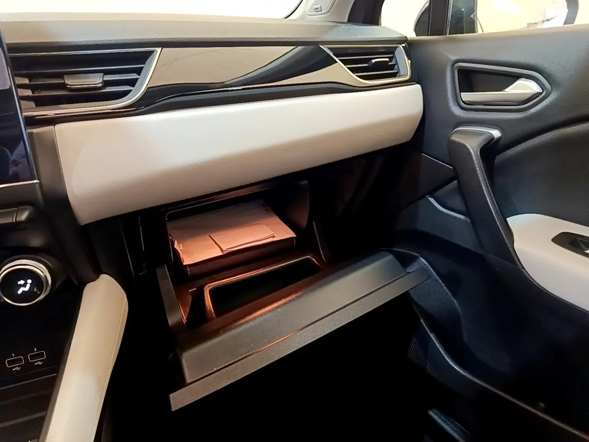 Intérieur côté passager du Renault Captur noir 2021, avec boîte à gants ouverte et tableau de bord bicolore beige et noir.