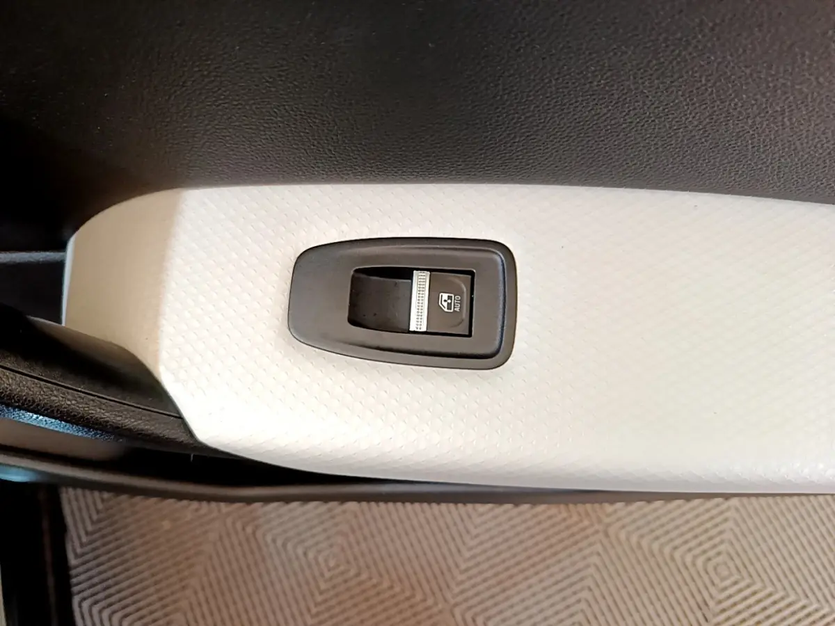 Gros plan sur le bouton de commande de lève-vitre avant droit, intérieur blanc texturé du Renault Captur noir 2021.