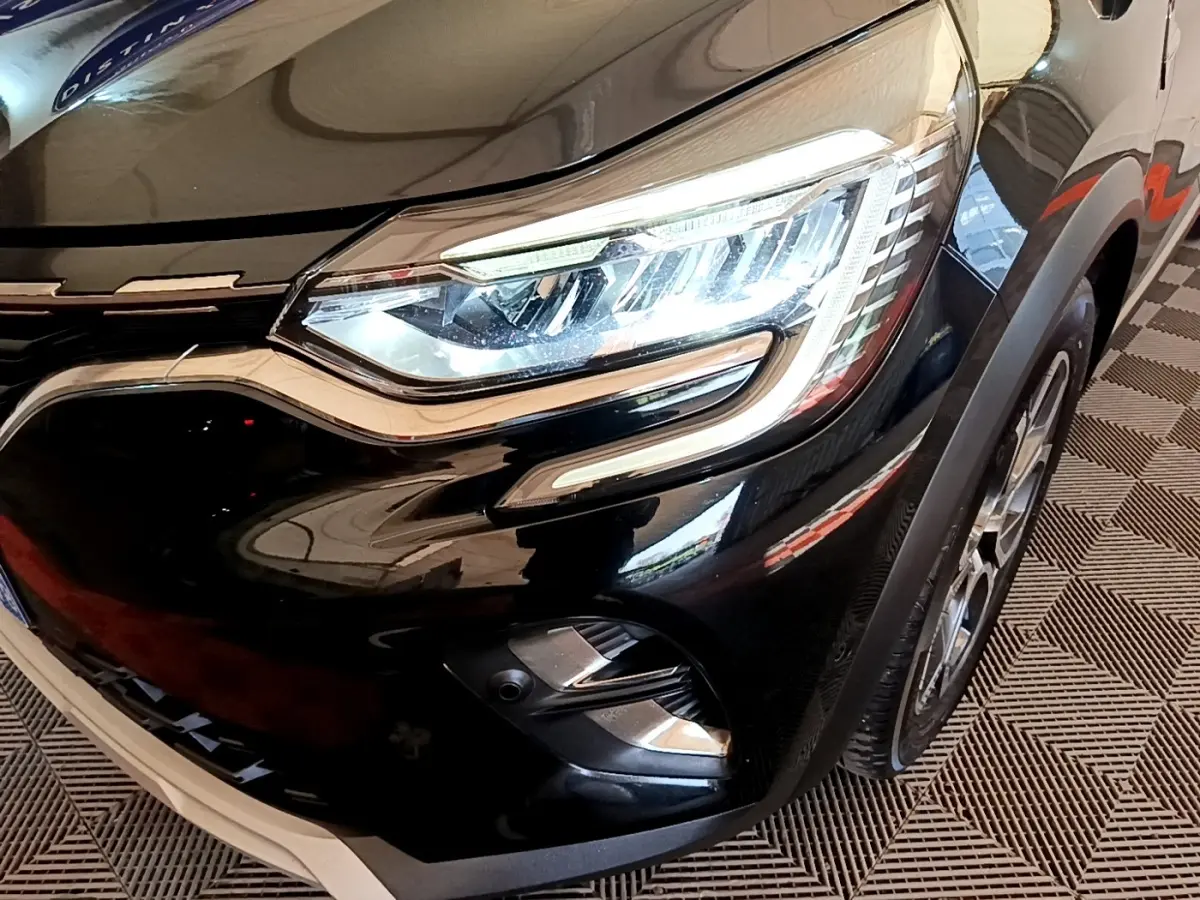 Gros plan sur l'avant droit noir brillant du Renault Captur 2021, mettant en valeur son phare LED et la calandre chromée.