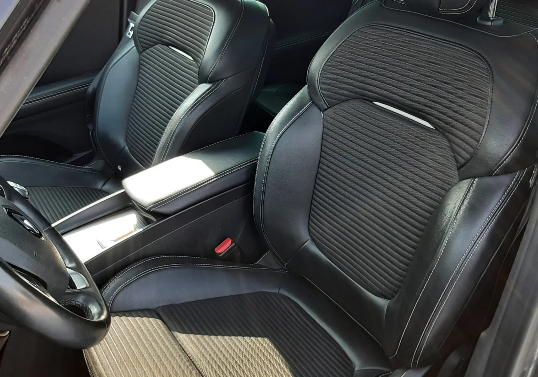 Vue intérieure rapprochée des sièges avant en cuir noir avec surpiqûres blanches du Renault Scénic IV gris cassiopée.