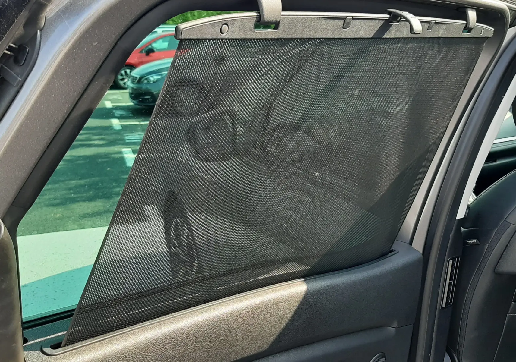 Détail de la porte arrière droite ouverte du Renault Scenic IV gris Cassiopée avec pare-soleil en filet noir.