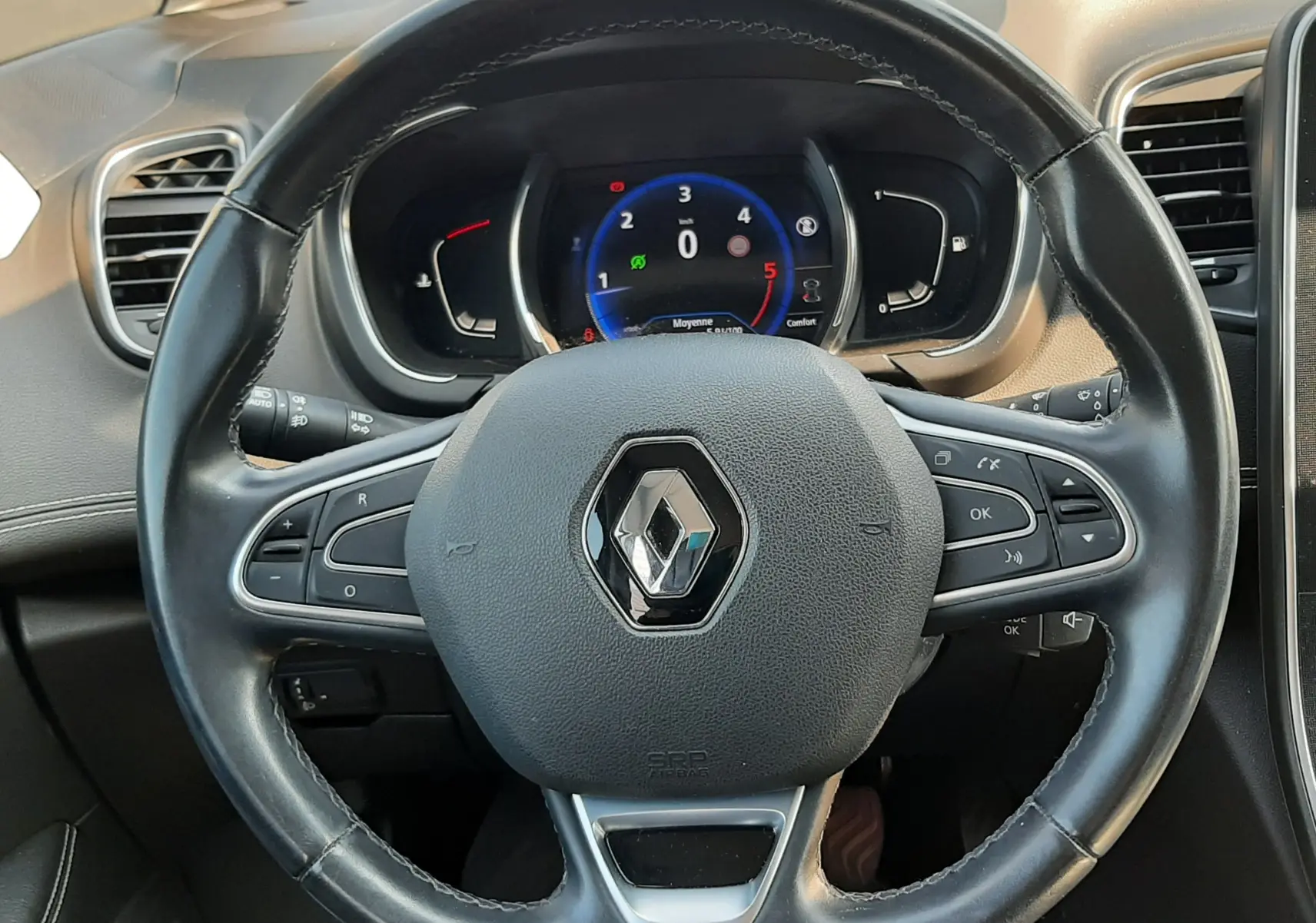 Vue intérieure centrée sur le volant noir du Renault Scénic IV 2018 avec tableau de bord numérique allumé.