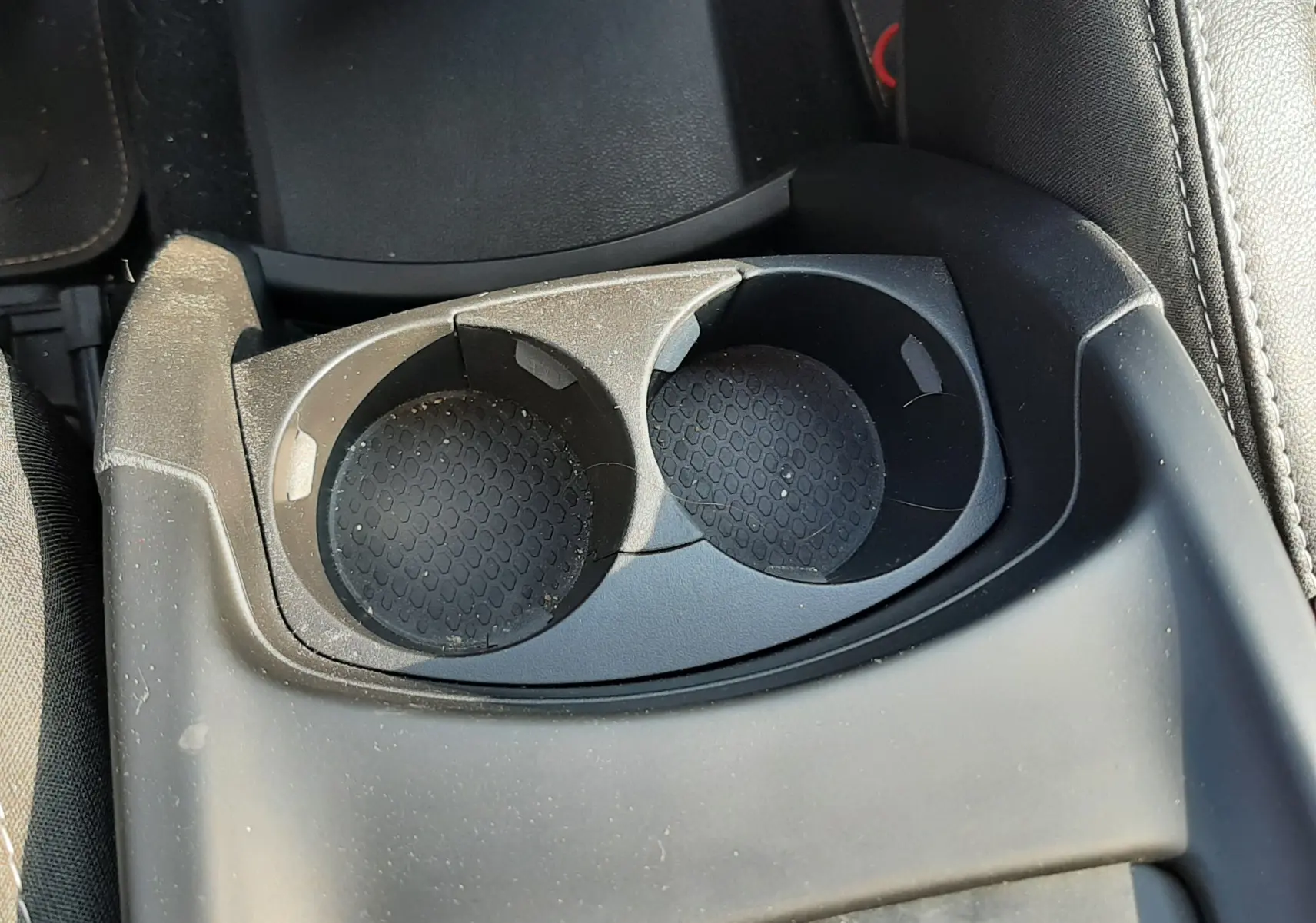 Gros plan sur les porte-gobelets noirs et la console centrale du Renault Scénic IV gris cassiopée avec intérieur noir.