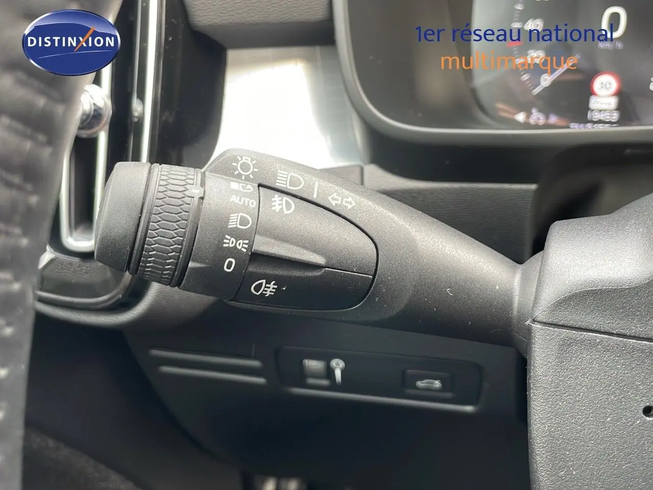 Gros plan sur la commande des phares à gauche du volant dans l'habitacle d'un Volvo XC40 noir Onyx 2021.