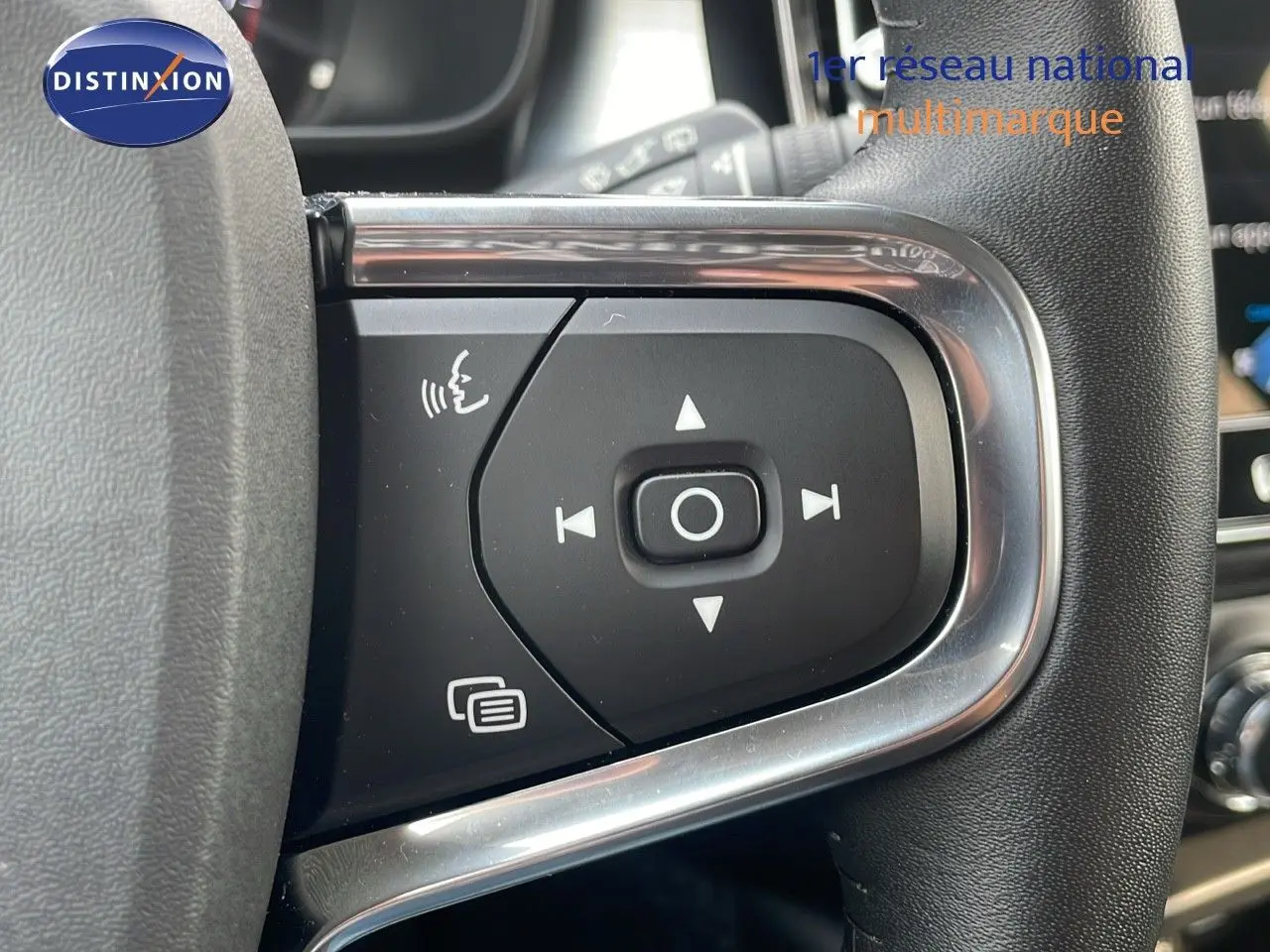 Gros plan sur les commandes au volant du Volvo XC40 noir Onyx Metal, mettant en valeur les boutons de navigation et de commande vocale.