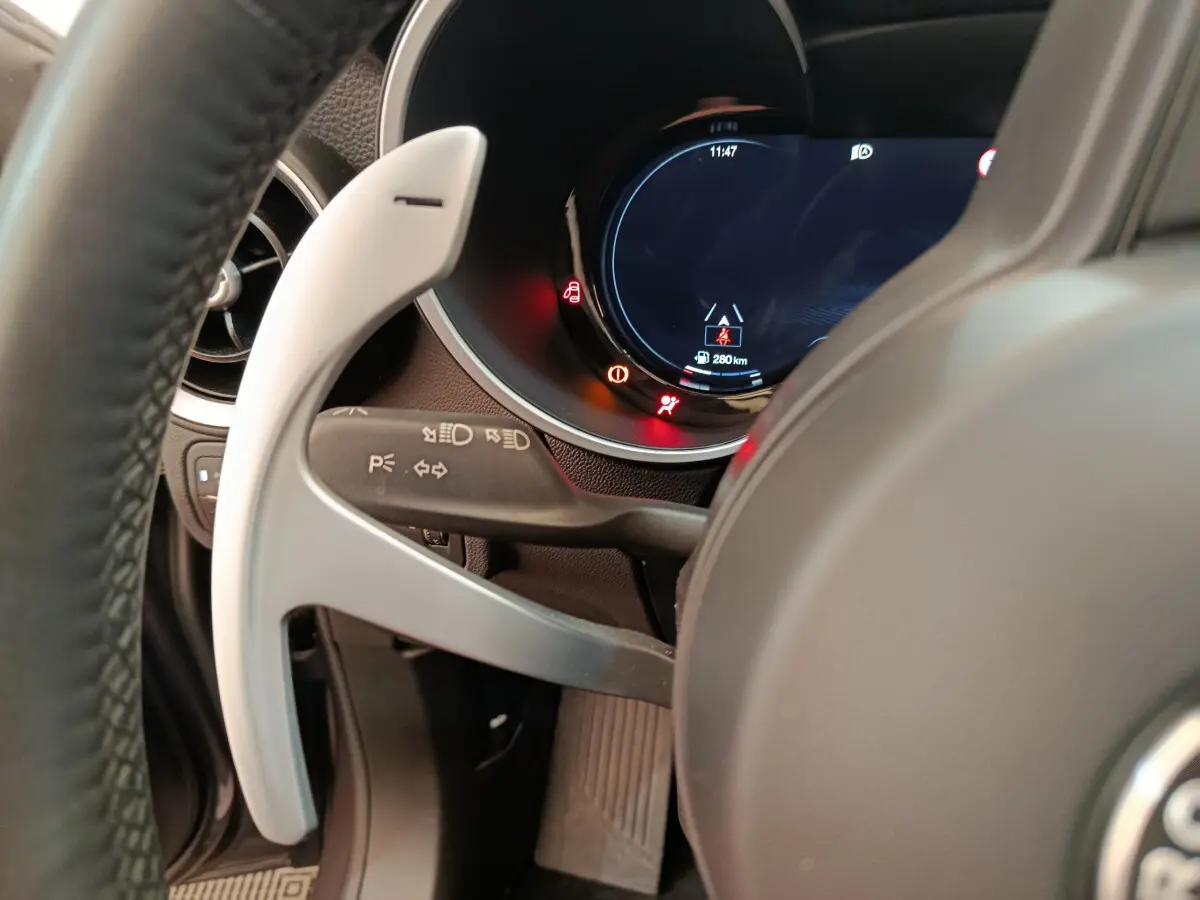 Gros plan sur le volant et le combiné d'instruments numérique de l'Alfa Romeo Stelvio gris foncé 2024, côté gauche.