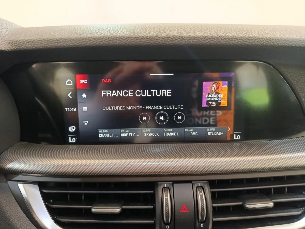 Écran tactile central du tableau de bord gris foncé de l'Alfa Romeo Stelvio Sprint 2024 affichant une radio DAB.
