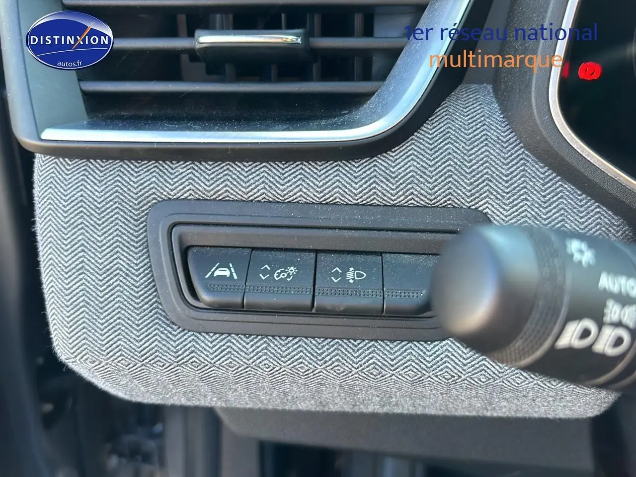 Gros plan sur les commandes d'assistance au conducteur avec habillage textile gris à motifs chevrons dans Renault Clio V gris Pizzara.