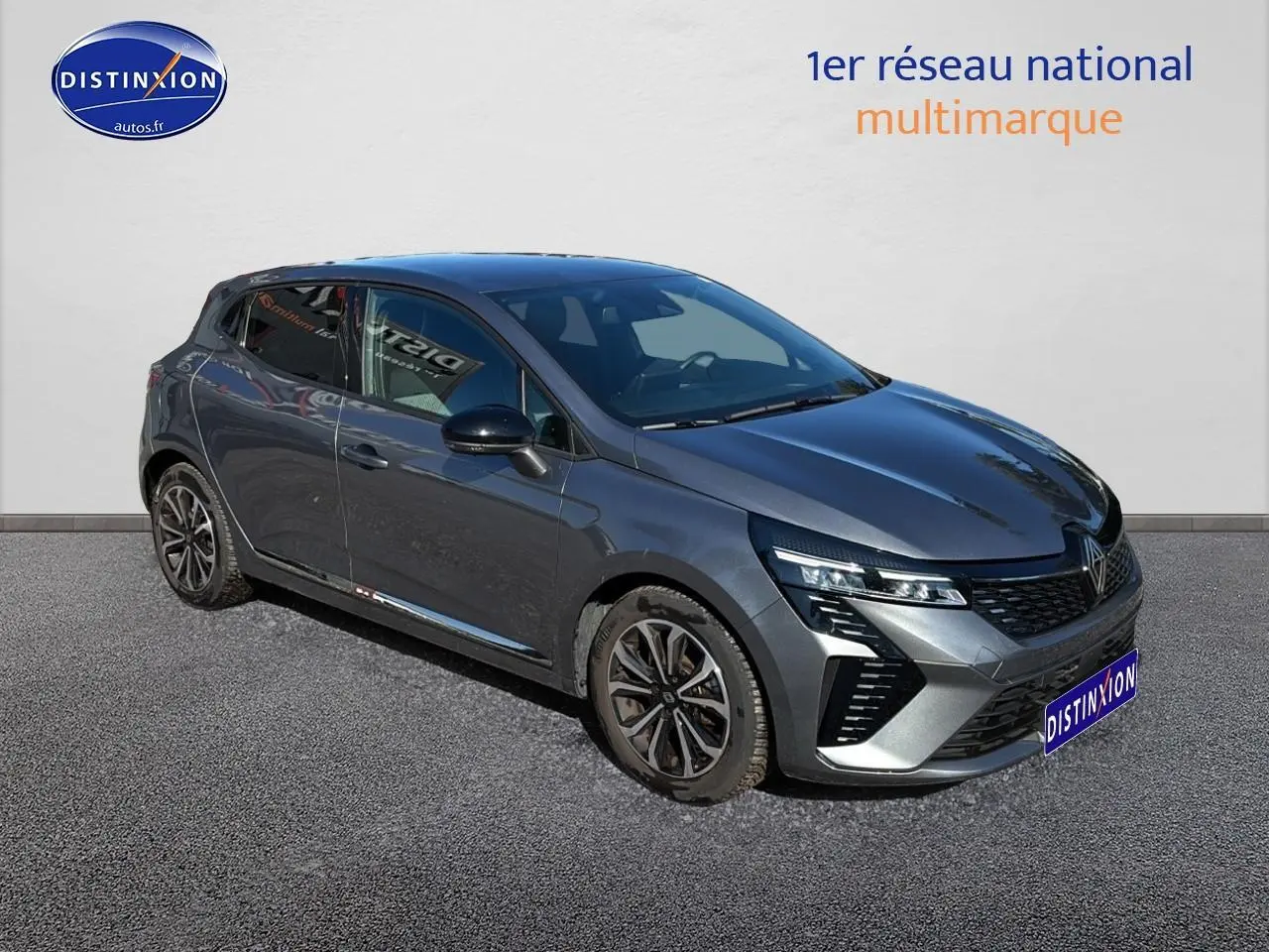 Renault Clio V gris pizzara vue 3/4 avant droit, calandre chromée et jantes alliage noires distinctives.