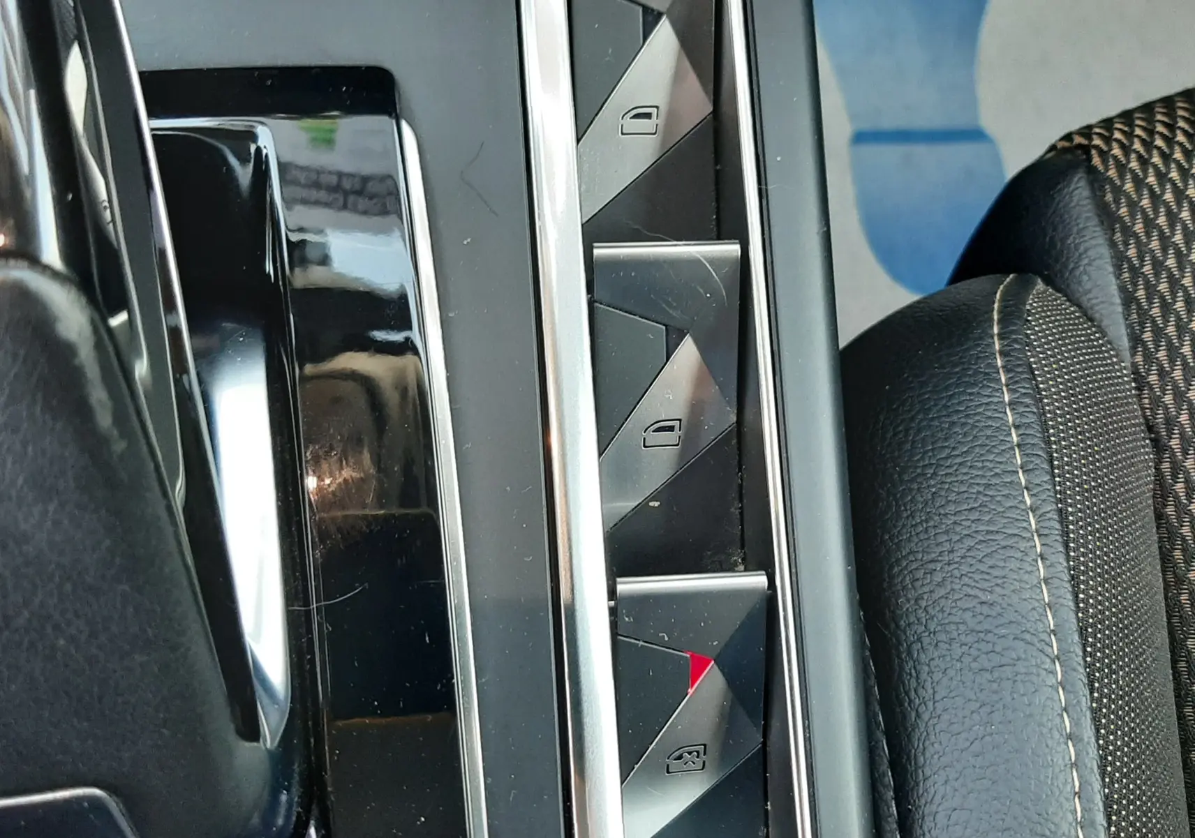 Gros plan sur les commandes de lève-vitres et verrouillage central, avec sellerie noire et tissu à motifs sur DS3 Crossback.