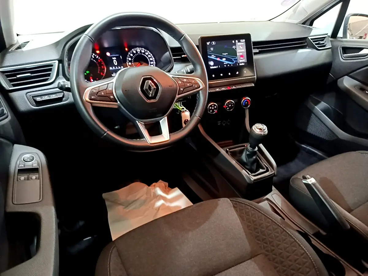 Vue intérieure avant droite du tableau de bord et volant cuir de la Renault Clio Business TCe 90 2021 avec écran tactile et boîte manuelle.