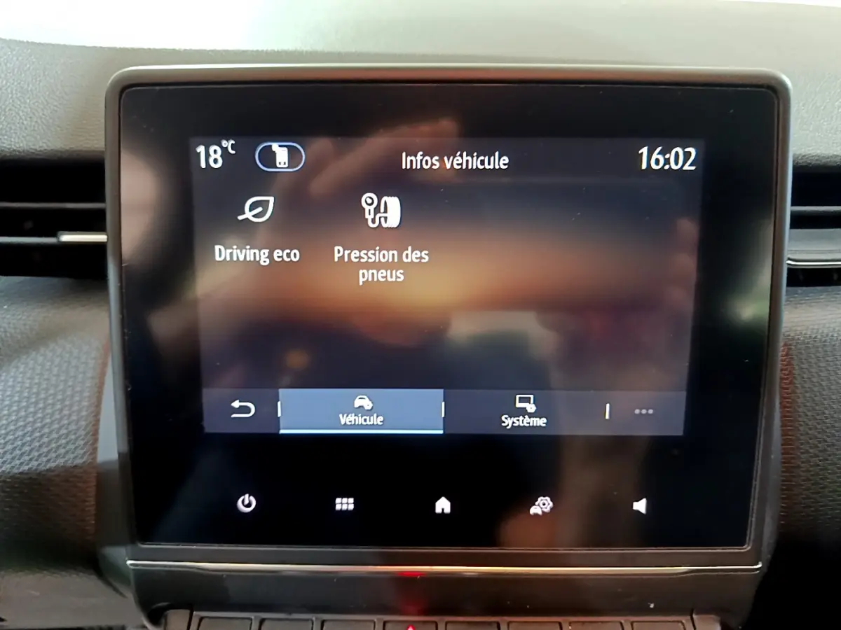 Écran tactile central affichant les infos véhicule dans l'habitacle d'une Renault Clio Business blanc, vue frontale rapprochée.