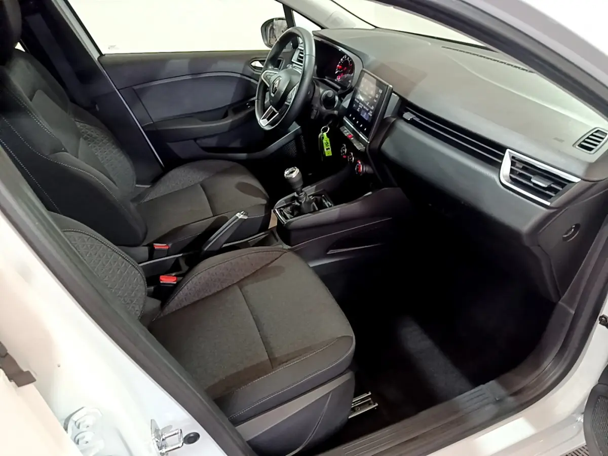 Intérieur avant droit d'une Renault Clio Business blanche, sièges noirs, volant multifonctions et écran tactile central visible.