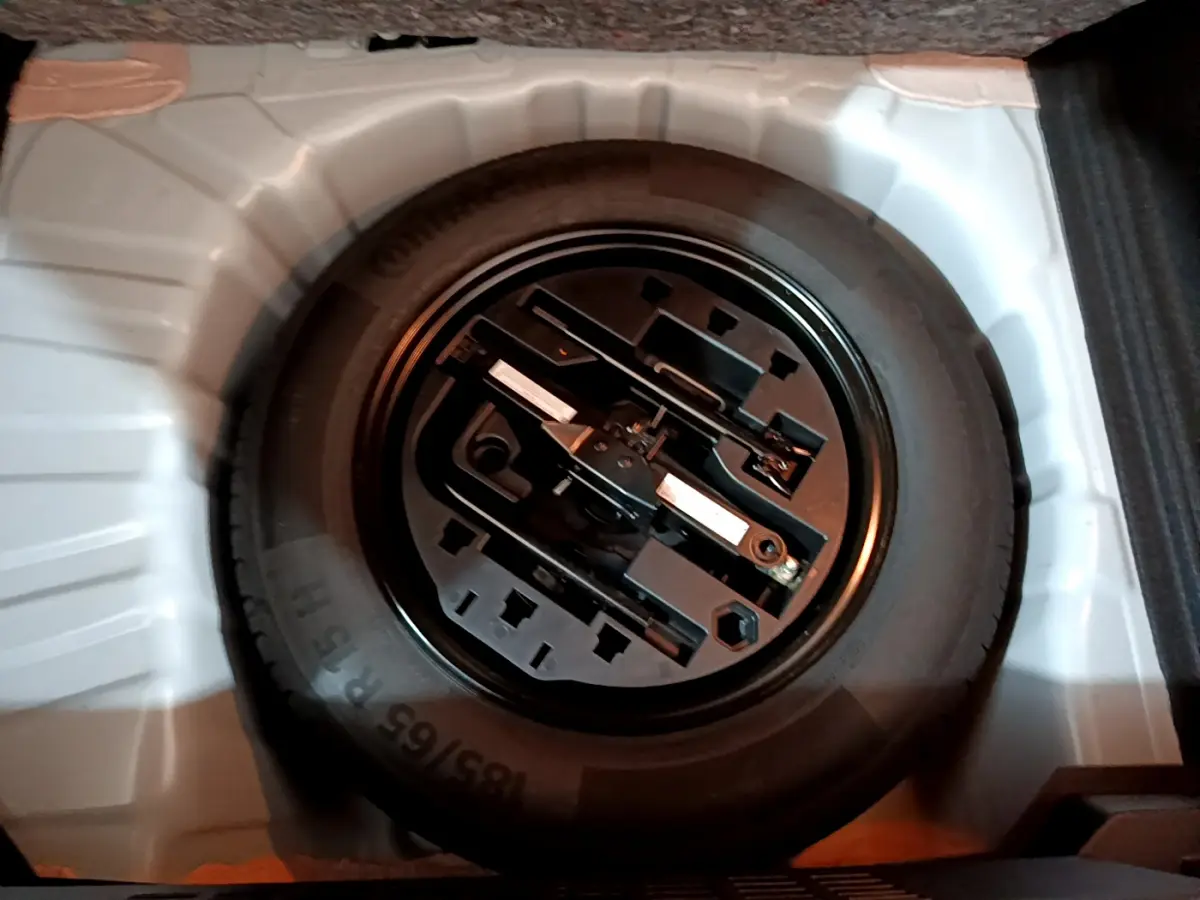 Roue de secours noire avec outils de changement dans le coffre blanc d'une Renault Clio Business TCe 90 2021.