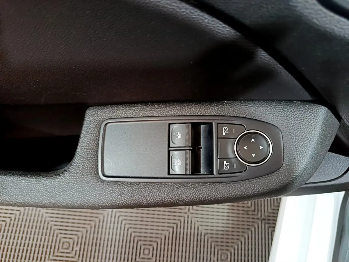 Gros plan sur les commandes de lève-vitres et réglage des rétroviseurs côté conducteur d'une Renault Clio blanche 2021.