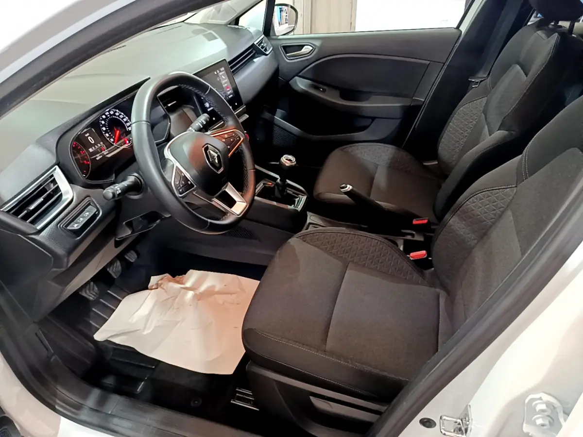 Intérieur avant droit de la Renault Clio Business TCe 90 blanc, volant cuir, sièges tissu gris et tableau de bord moderne.