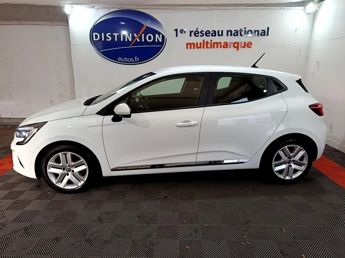 Profil côté gauche d'une Renault Clio Business TCe 90 blanche 2021, avec jantes alliage et vitres teintées, en intérieur showroom.
