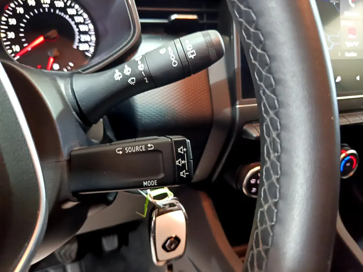 Gros plan sur la colonne de direction et le volant en cuir noir de la Renault Clio Business TCe 90 blanche de 2021.