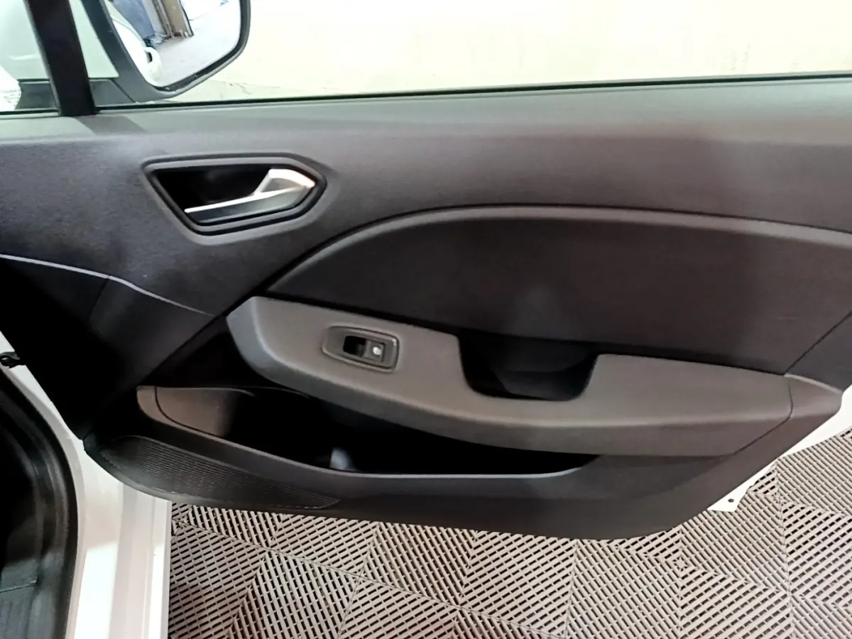 Intérieur montrant la porte côté gauche de la Renault Clio Business TCe 90 blanche, avec poignée et commande de fenêtre.