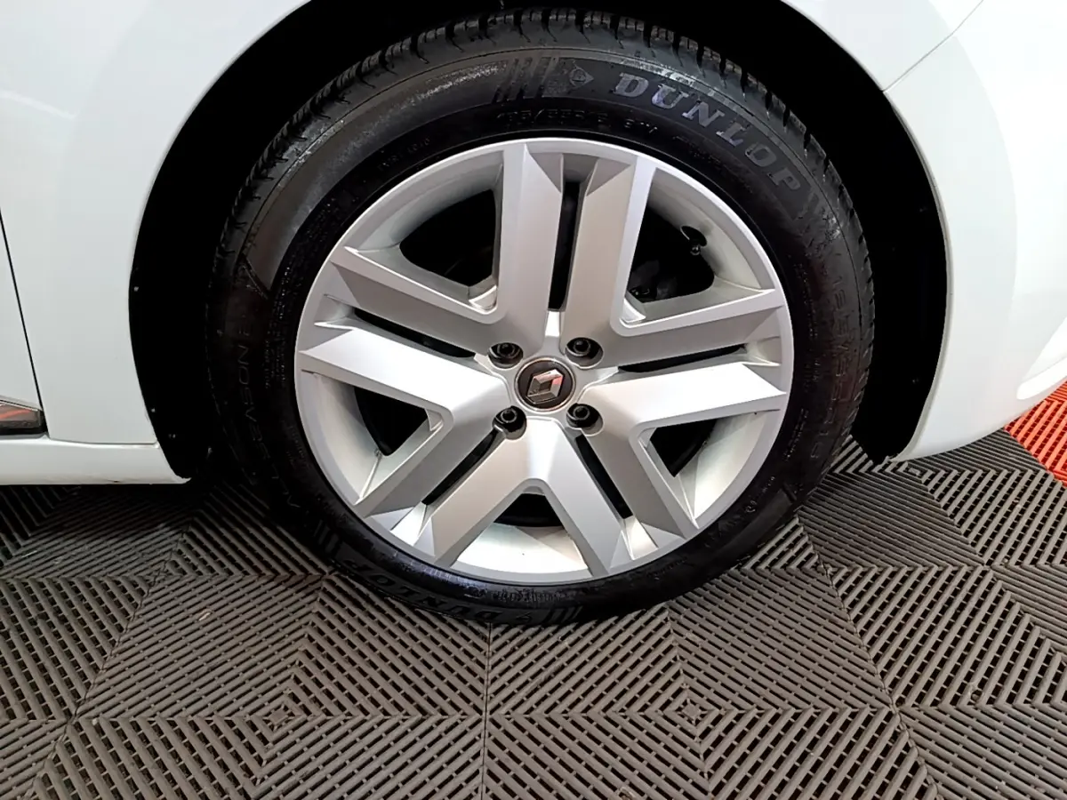 Gros plan sur la roue avant gauche blanche d'une Renault Clio Business TCe 90 avec jante alliage et pneu Dunlop.