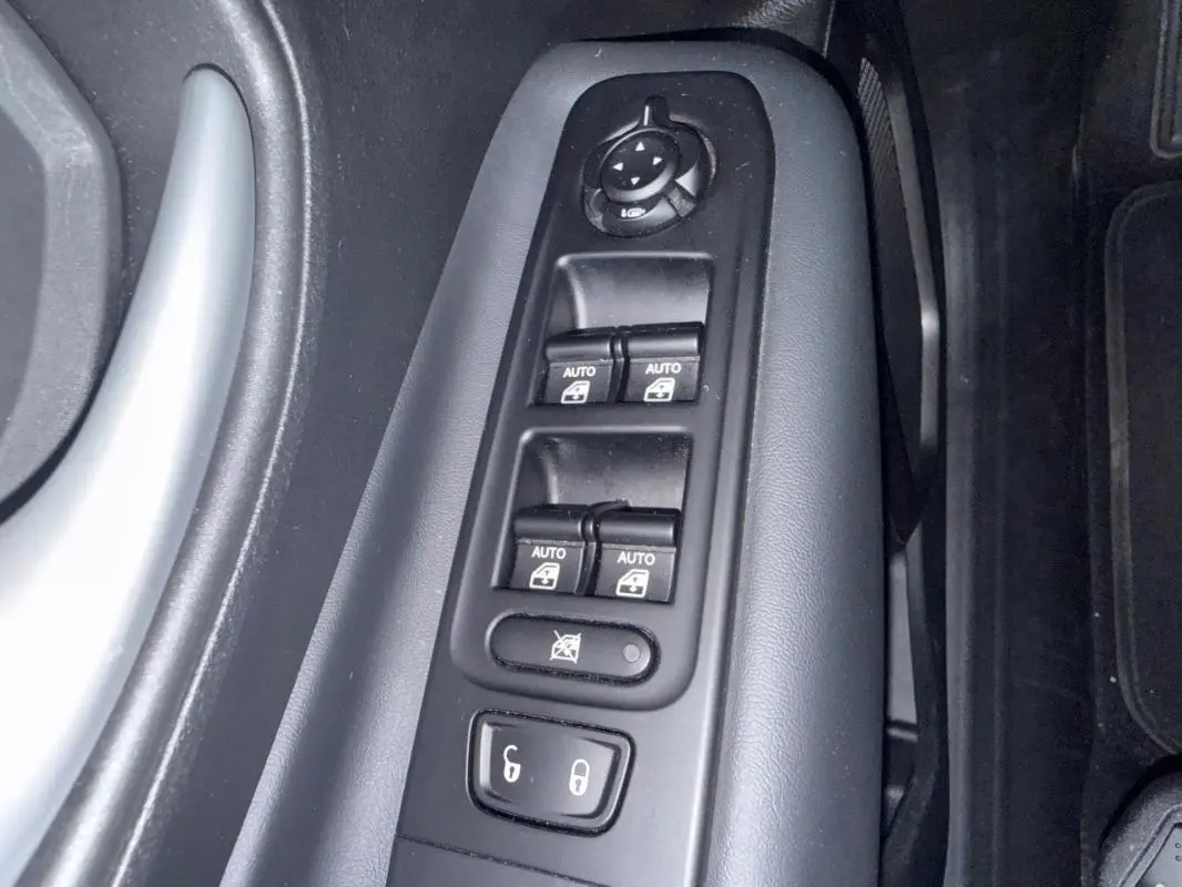 Détail des commandes des vitres électriques et rétroviseurs côté conducteur du Jeep Renegade gris anthracite 2024.