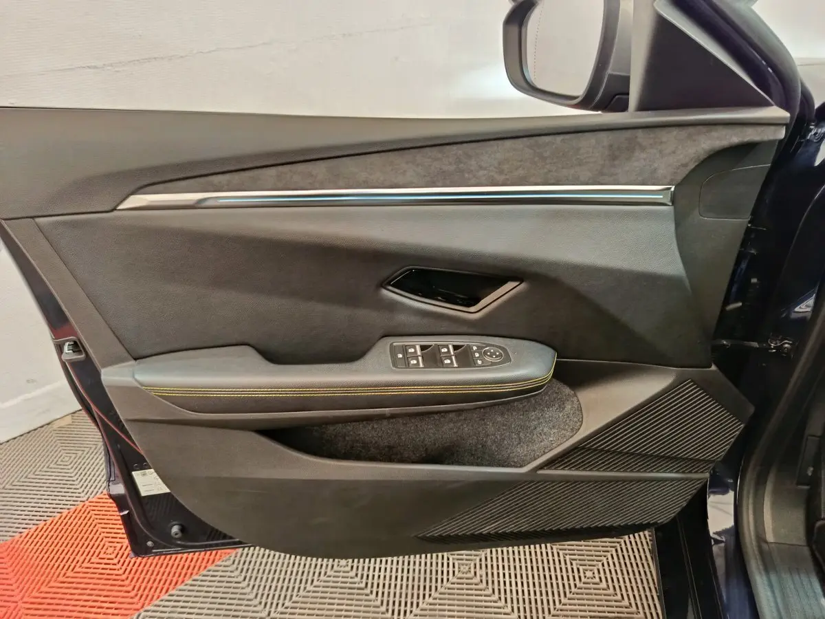 Vue côté intérieur de la porte avant gauche de la Renault Mégane Techno EV60 220ch bleu, avec commandes électriques et surpiqûres jaunes.