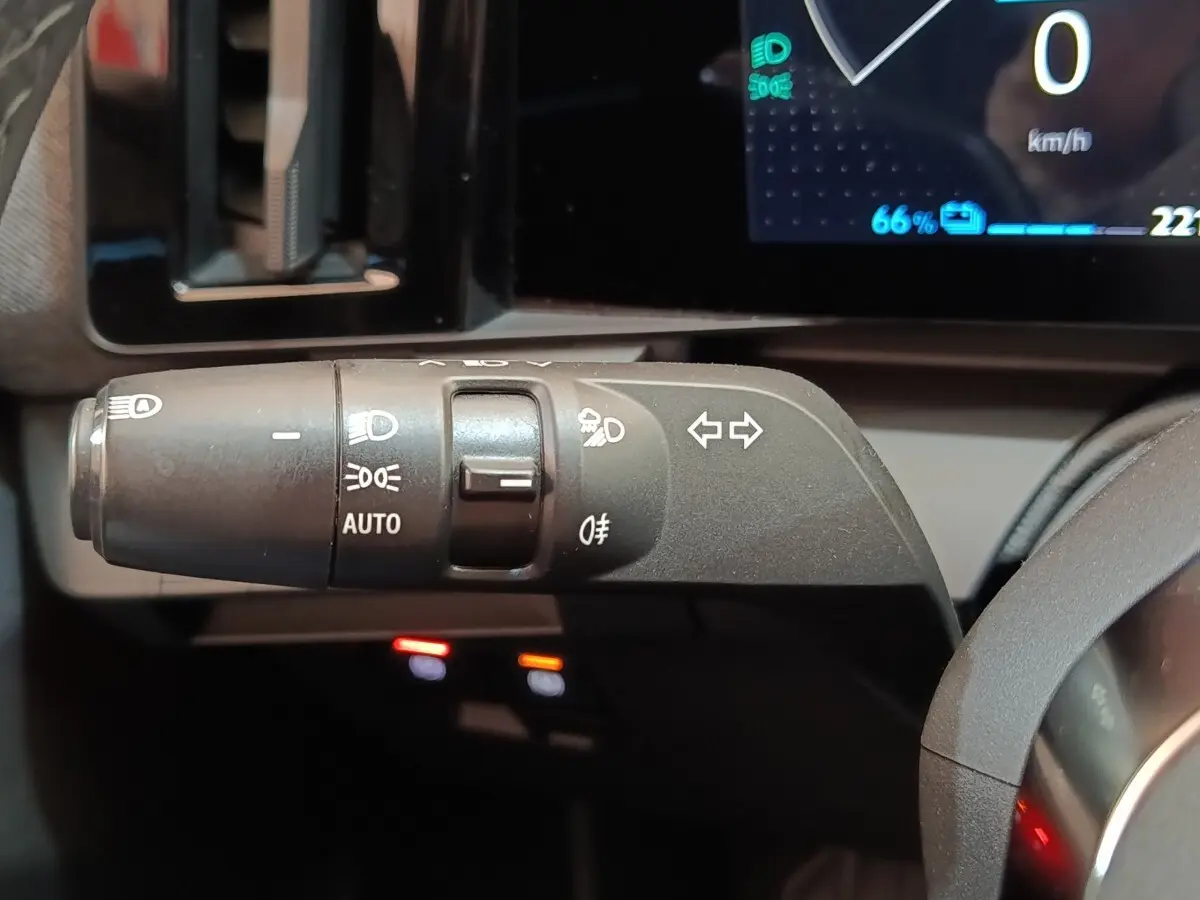Gros plan sur la commande des feux et clignotants à gauche du volant dans le tableau de bord de la Renault Mégane bleu électrique 2023.