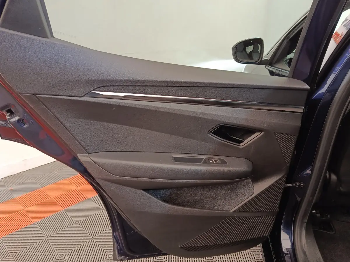 Vue intérieure de la porte arrière droite bleu foncé de la Renault Megane Techno EV60 avec garniture noire et commandes de fenêtre.