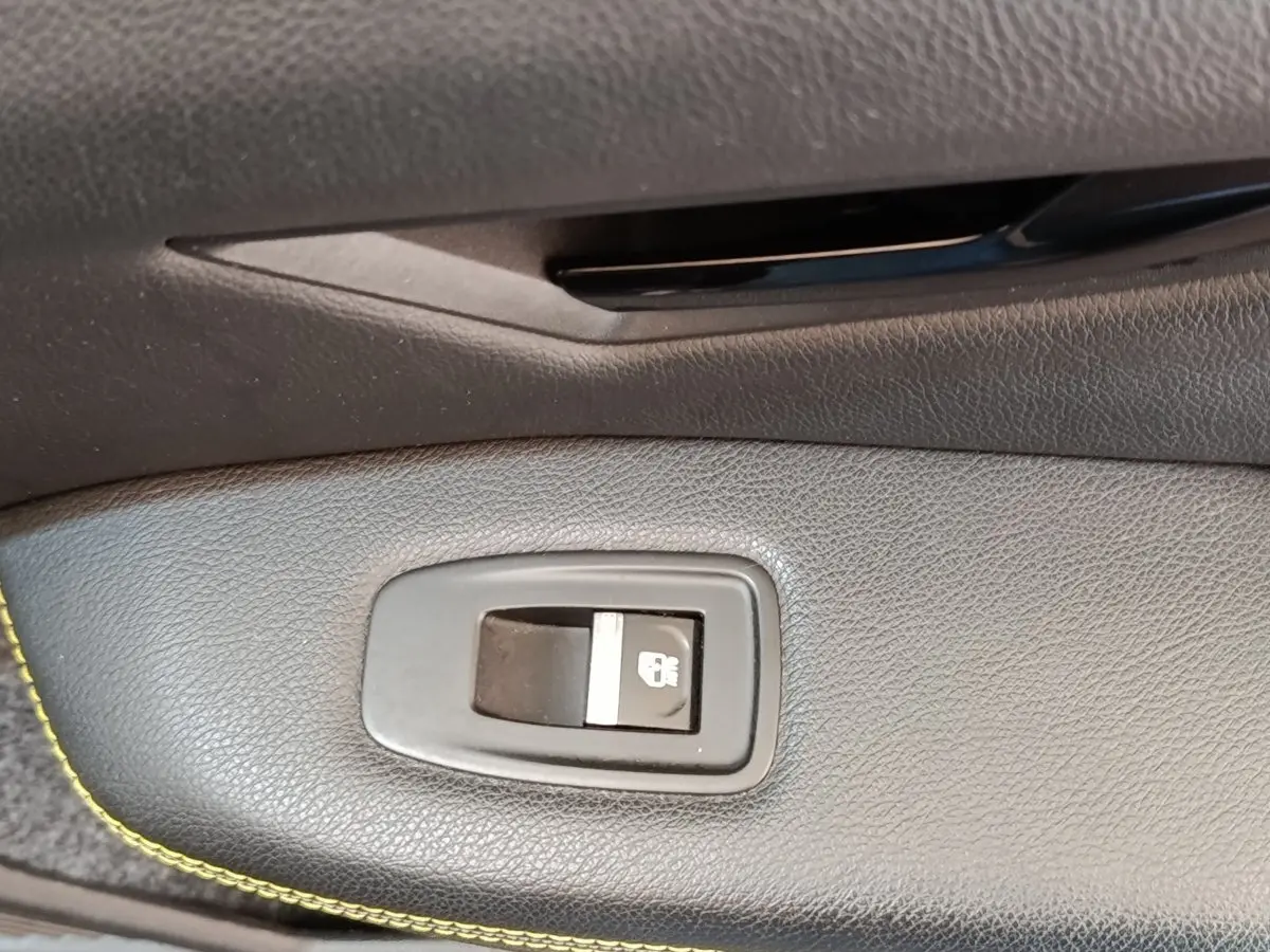 Bouton de verrouillage des portes en gros plan sur la porte intérieure noire de la Renault Mégane électrique bleu 2023.