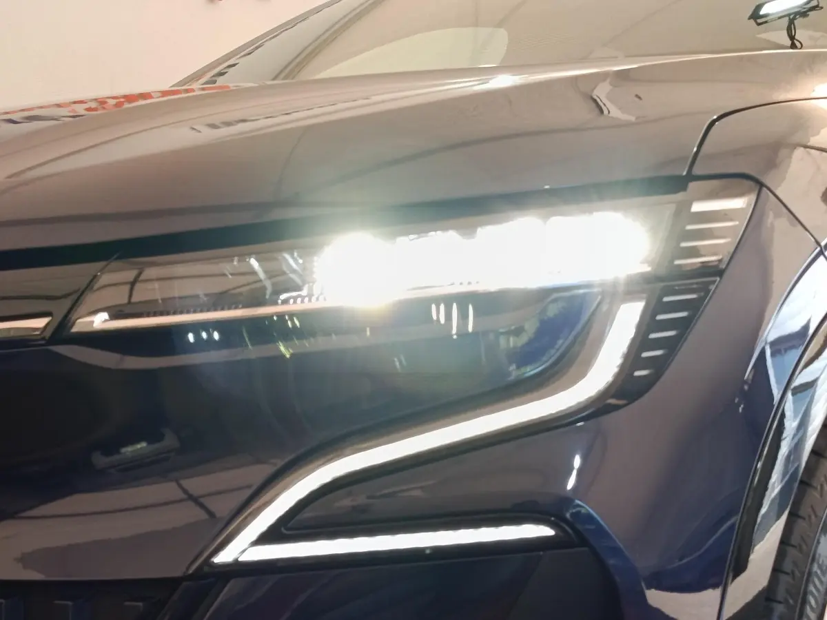 Gros plan sur le phare avant droit allumé de la Renault Mégane Techno EV60 bleu électrique 2023.
