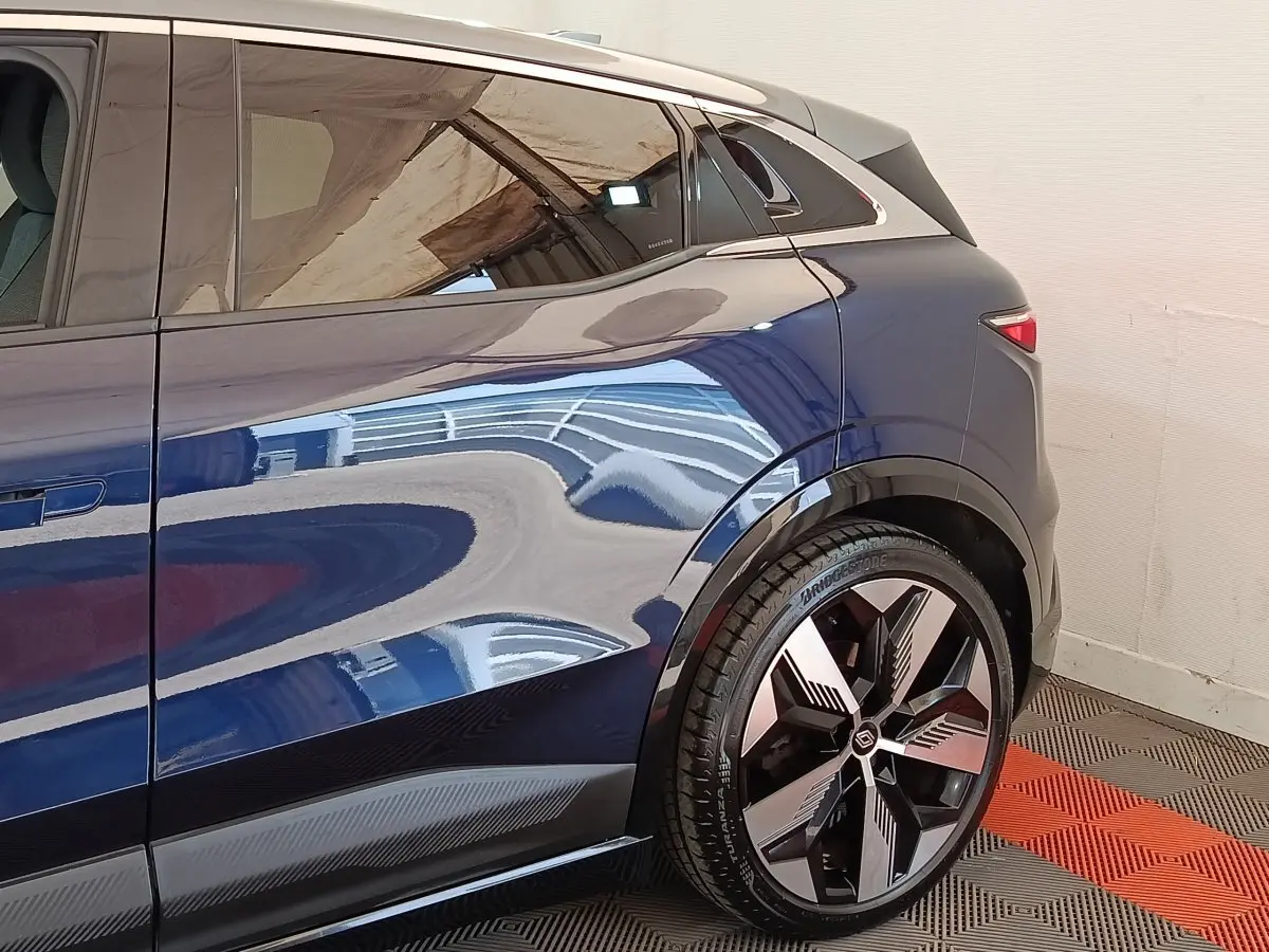 Vue latérale arrière droite d'une Renault Mégane Techno EV60 bleu électrique avec jante alliage distinctive.