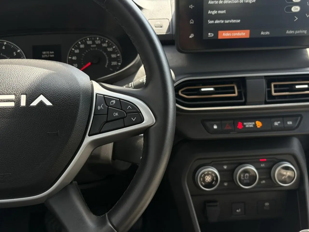 Gros plan sur le volant Dacia et la console centrale avec écran tactile et commandes de climatisation du Sandero Stepway.