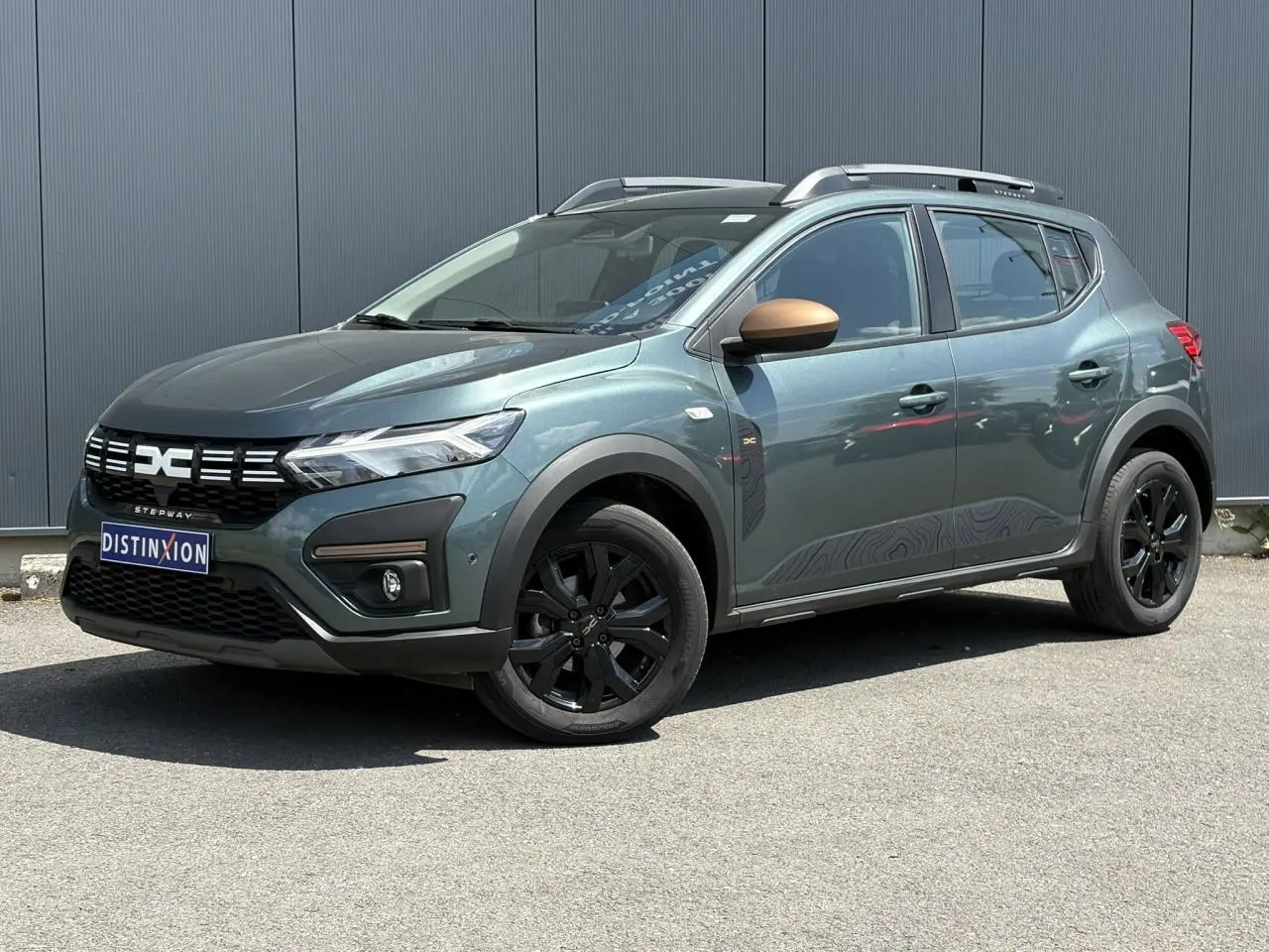 Dacia Sandero Stepway 2025 Vert Cèdre en 3/4 avant droit avec jantes noires et coques de rétroviseur cuivrées.